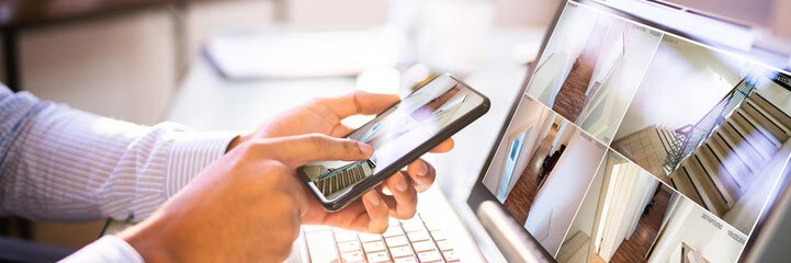 person using phone and laptop to view home remotely
